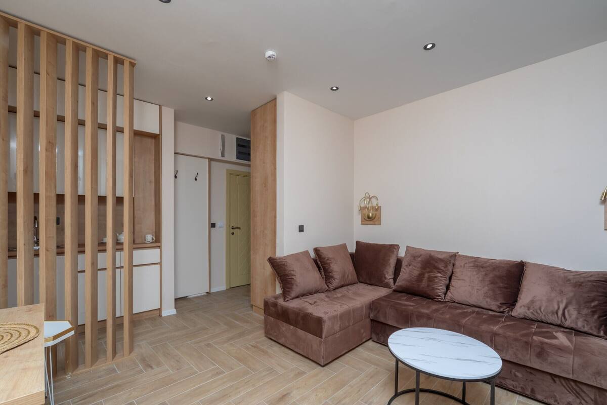 Ein modernes Wohnzimmer mit einem braunen Ecksofa, einem runden Couchtisch und einer Holzwand.