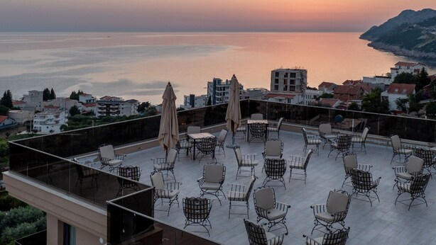 Terraza en la azotea con mobiliario exterior y vista al mar al atardecer.