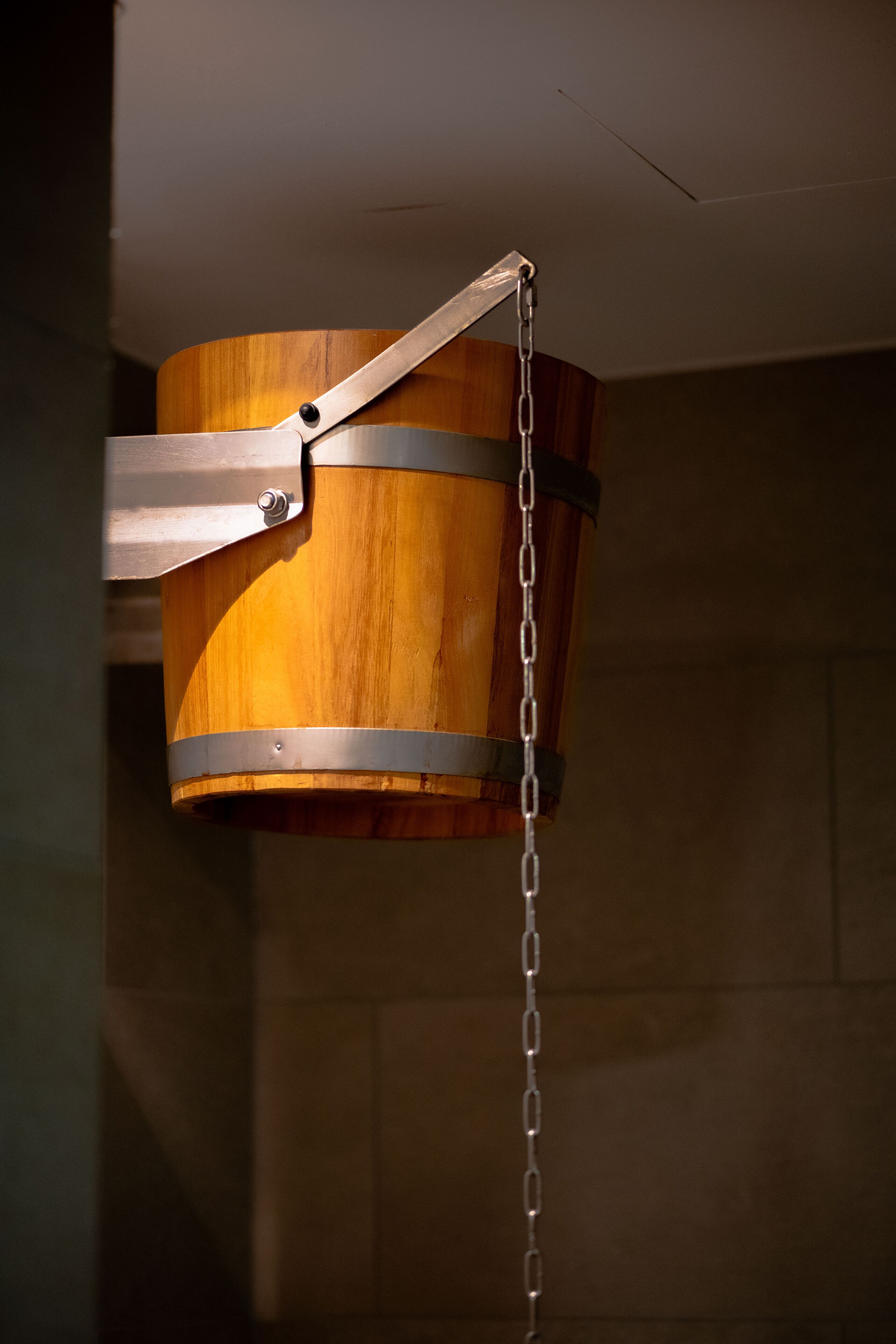 A wooden bucket with a metal chain and a metal bracket.