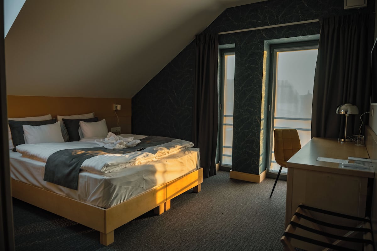 A hotel room with a bed, desk, and chair.
