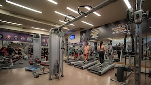 Un gimnasio con cintas de correr, máquinas de pesas y un cartel en la pared.