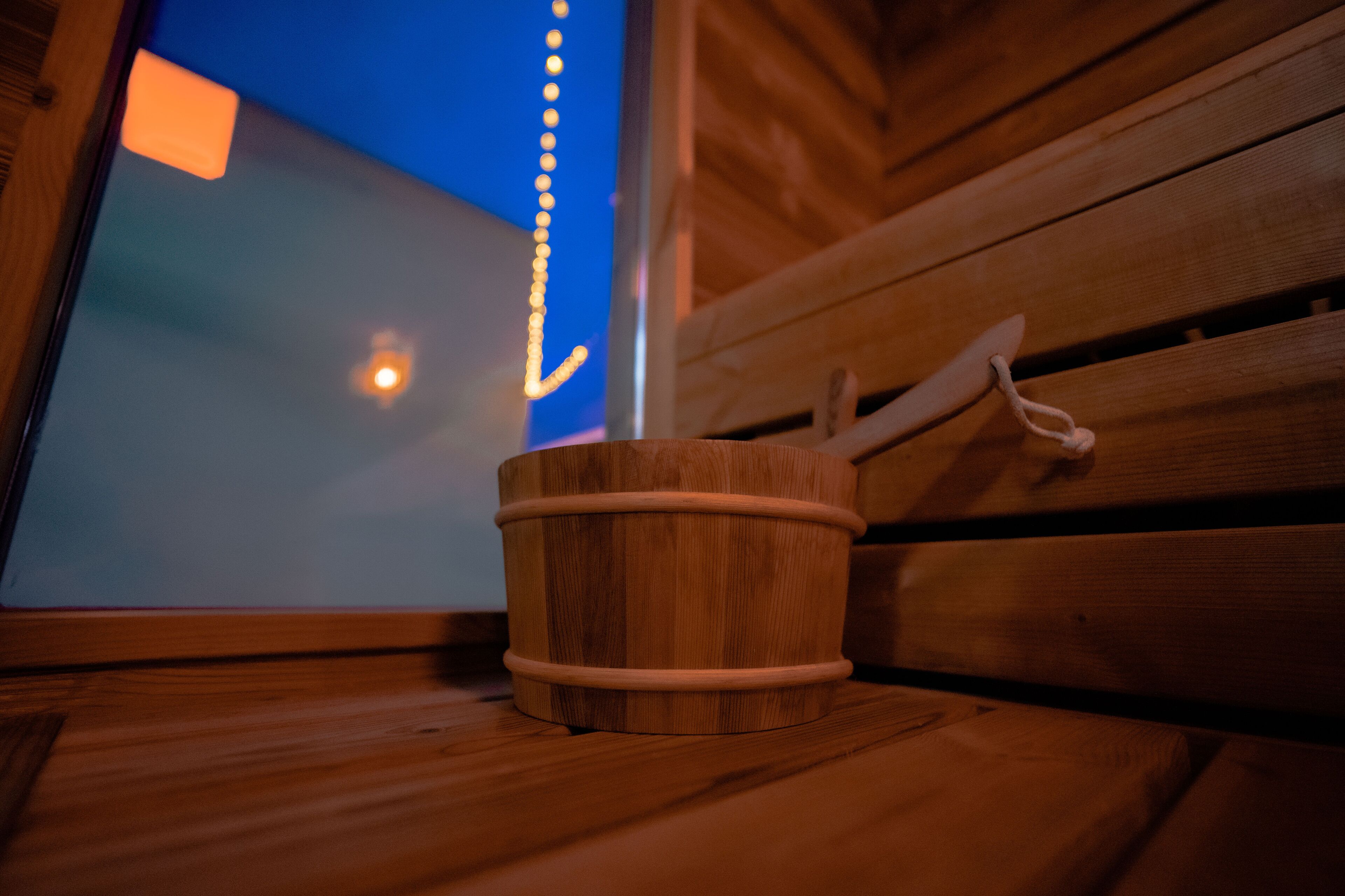 A wooden bucket on a bench with a window view.