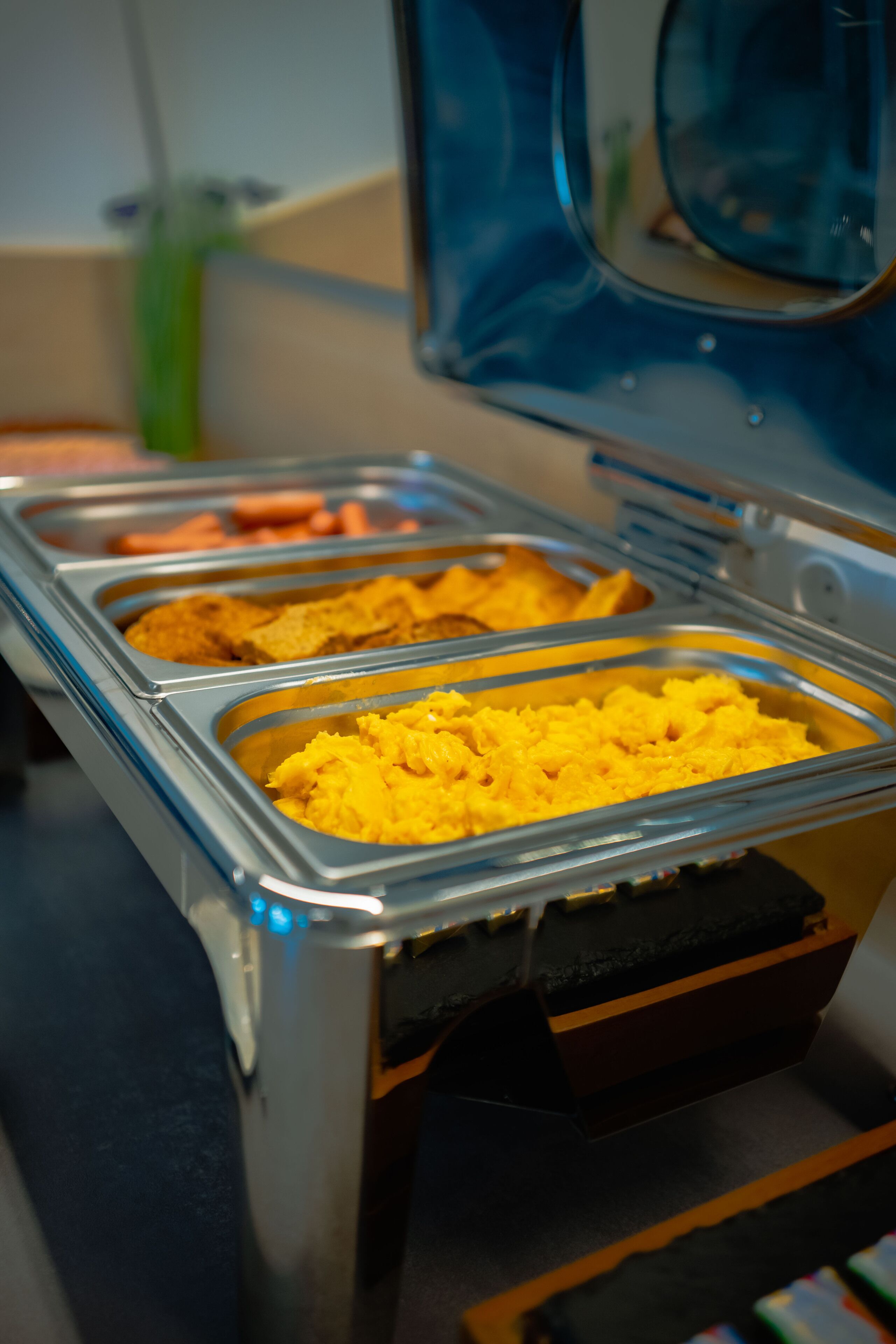 A buffet with various food items in metal trays.