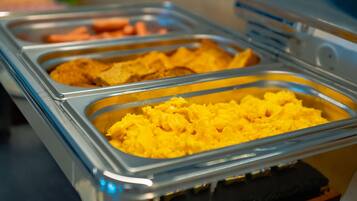 A buffet with various food items in metal trays.
