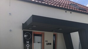 Entrada de hotel con diseño moderno, destacando un logotipo y una señalización que indica el nombre del hotel.