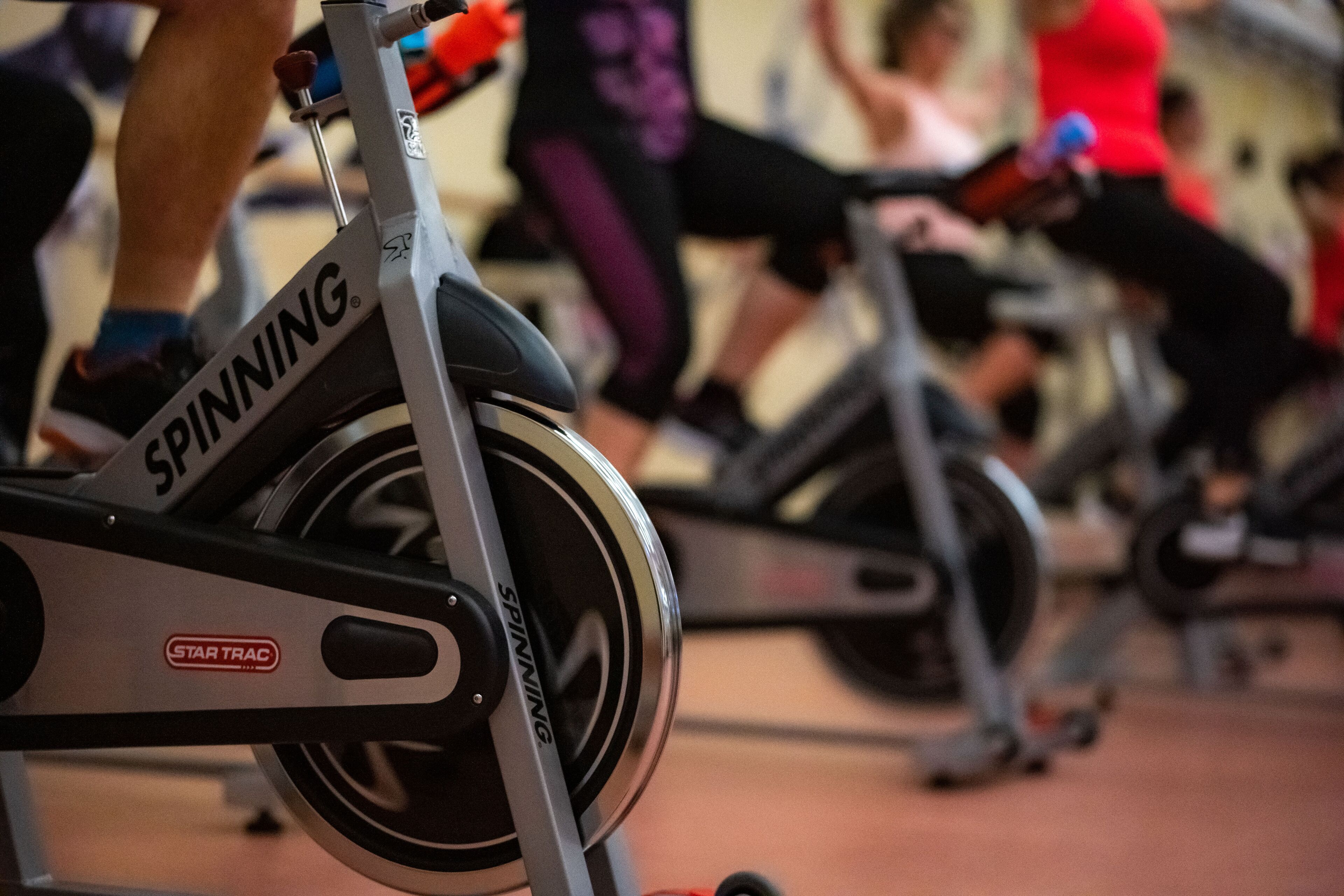 A stationary bike with the brand name "SPINNING" and "STAR TRAC" visible.