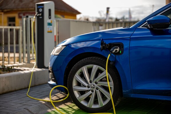 A blue car parked at a charging station with a yellow cable connected to it. - Eleven Business & Sport Hotel (Jászárokszállás)