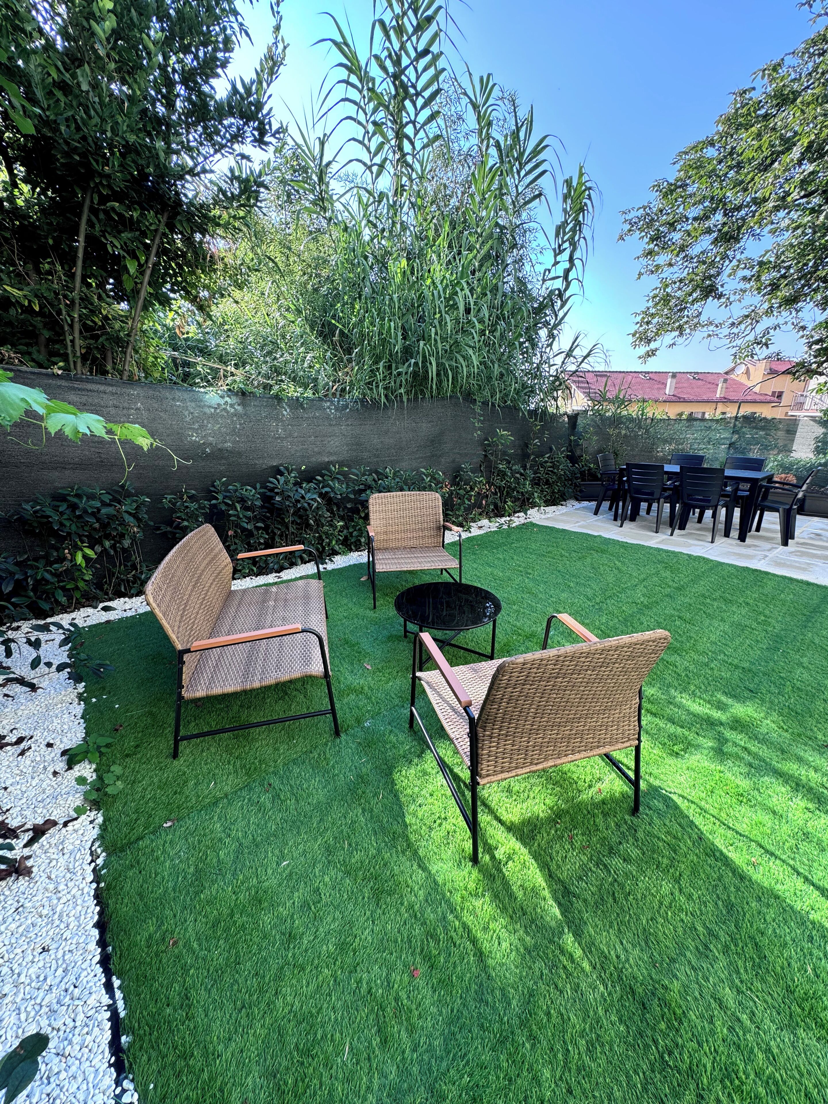 Un espace patio aménagé avec des meubles en osier, une table ronde et une petite table noire.