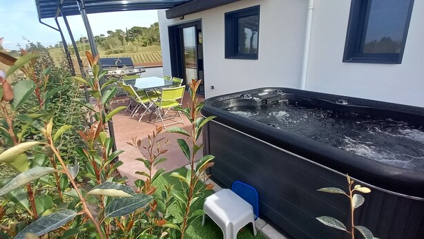 Un jacuzzi situé à l’extérieur d’un bâtiment, avec une table et des chaises à proximité.