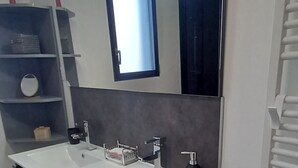 Une salle de bain moderne avec un meuble-lavabo à deux vasques, un grand miroir et un radiateur intégré.
