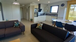 Un salon moderne avec deux canapés et un coin repas comprenant une table et des chaises.