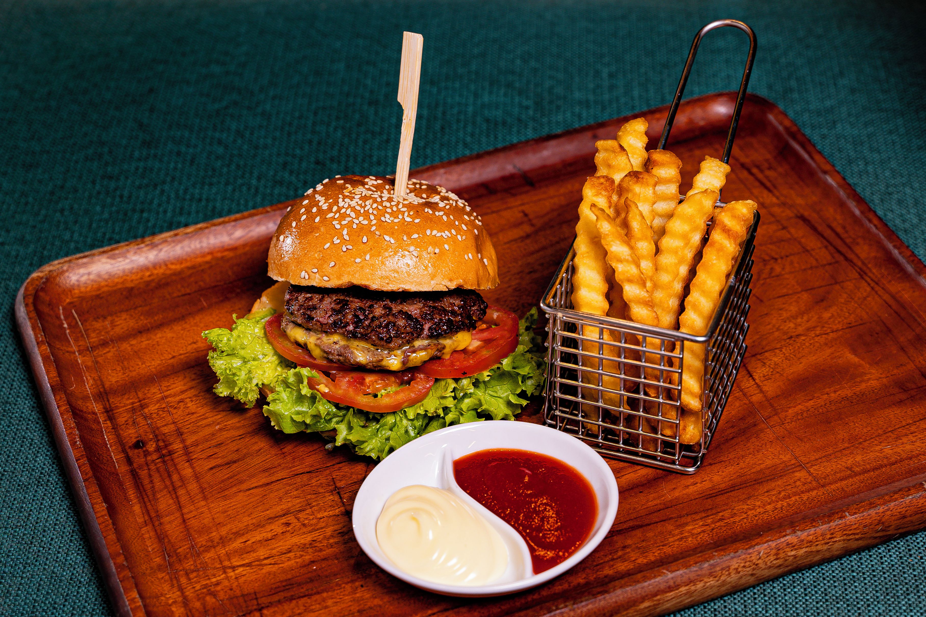A burger with lettuce, tomato, and a bun, accompanied by fries and a small bowl of ketchup.
