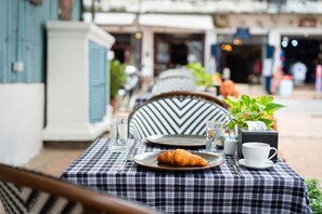Une table dressée avec un croissant, une tasse et une soucoupe, le tout sur une nappe à carreaux.