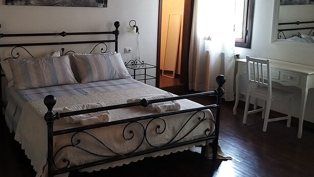 A bed with a metal frame, white bedding, and a small bedside table with a lamp. - B&B Villa Trotter (Mira)