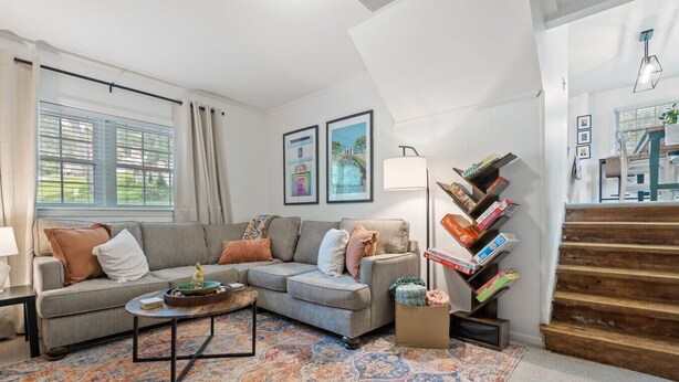 A living room with a sofa, coffee table, and a bookshelf with books. - The Juke Joint: Game Room, Pet-Friendly BHM Home! (Birmingham)