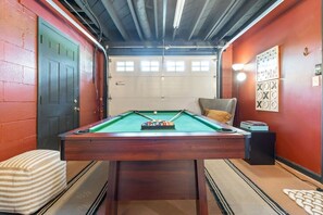 A pool table in a room with red walls, a door, and a window.
