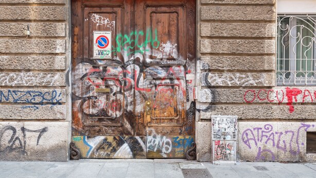 A weathered wooden door with graffiti and a no parking sign. - notaMi - Happy Stay - Naviglio Grande (Milan)
