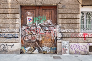 A weathered wooden door with graffiti and a no parking sign. - notaMi - Happy Stay - Naviglio Grande (Milan)