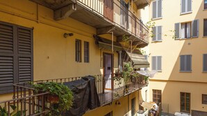 A yellow building with balconies, a door, and a small garden area with plants. - notaMi - Happy Stay - Naviglio Grande (Milan)