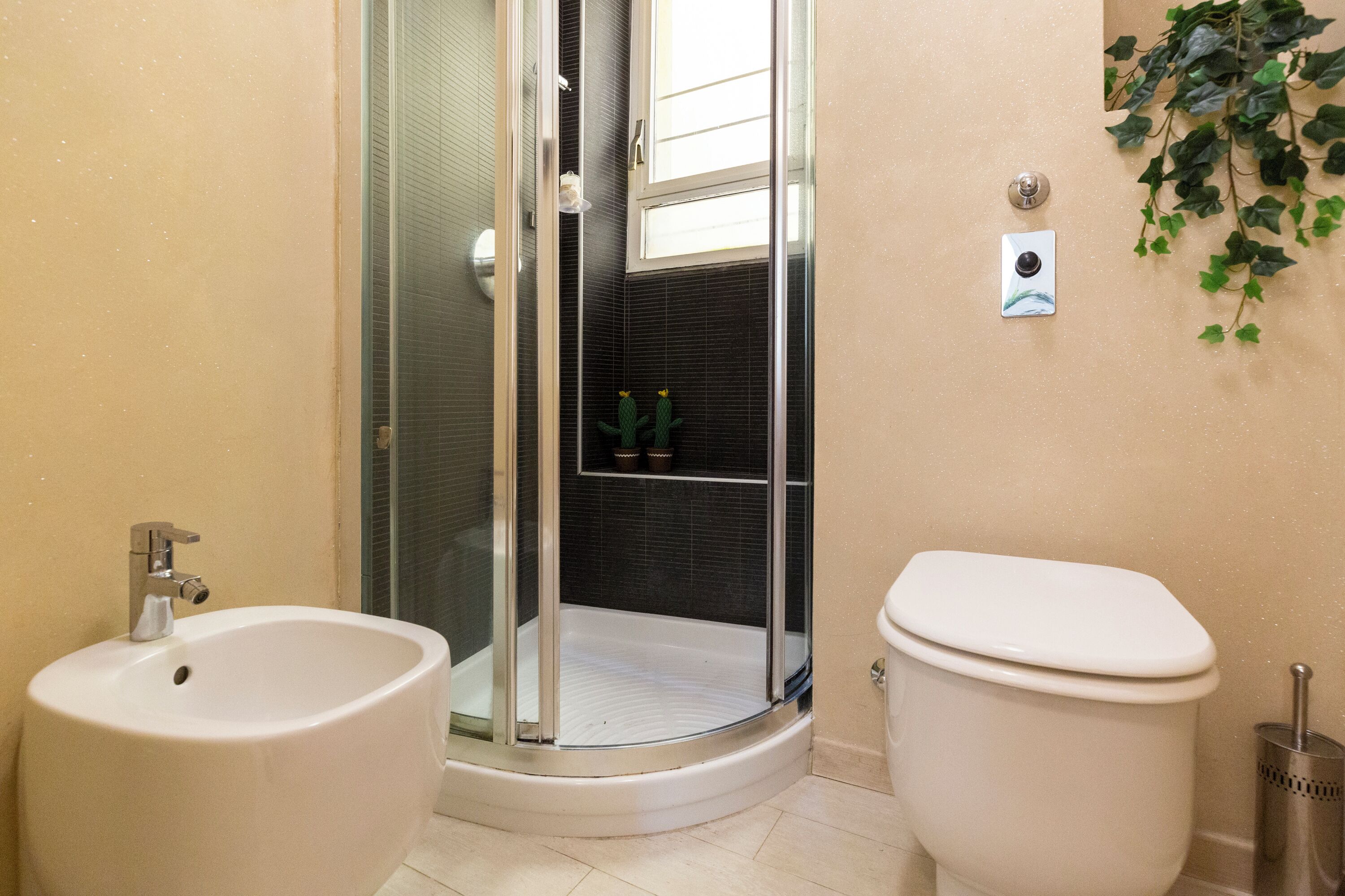 A bathroom with a glass shower enclosure, a bidet, and a toilet.