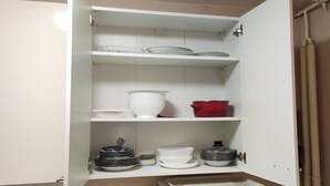 A kitchen with white cabinets, a sink, and a red pot on the middle shelf. - Sasa Apart (Beograd)