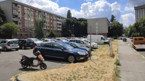 A parking lot with multiple cars and a scooter, surrounded by apartment buildings. - Sasa Apart (Beograd)