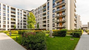 Un edificio de apartamentos moderno con varios balcones y un jardín bien cuidado.