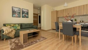 Una sala de estar moderna con un sofá verde, una mesa de centro de madera y un comedor con mesa y sillas.