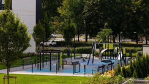 Un parque infantil con piscina, rodeado de árboles y un edificio.