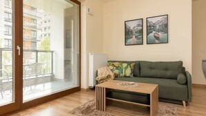 Una sala de estar con un sofá verde, una mesa de centro de madera y dos cuadros en la pared.