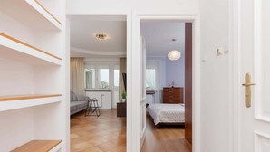 Hotellihuone, jossa on sänky, lipasto, tuoli ja näkymä kaupunkiin.