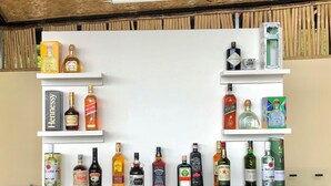 A bar area with multiple shelves displaying various liquor bottles and glasses. - Hannas Inn El Nido Palawan  (El Nido)