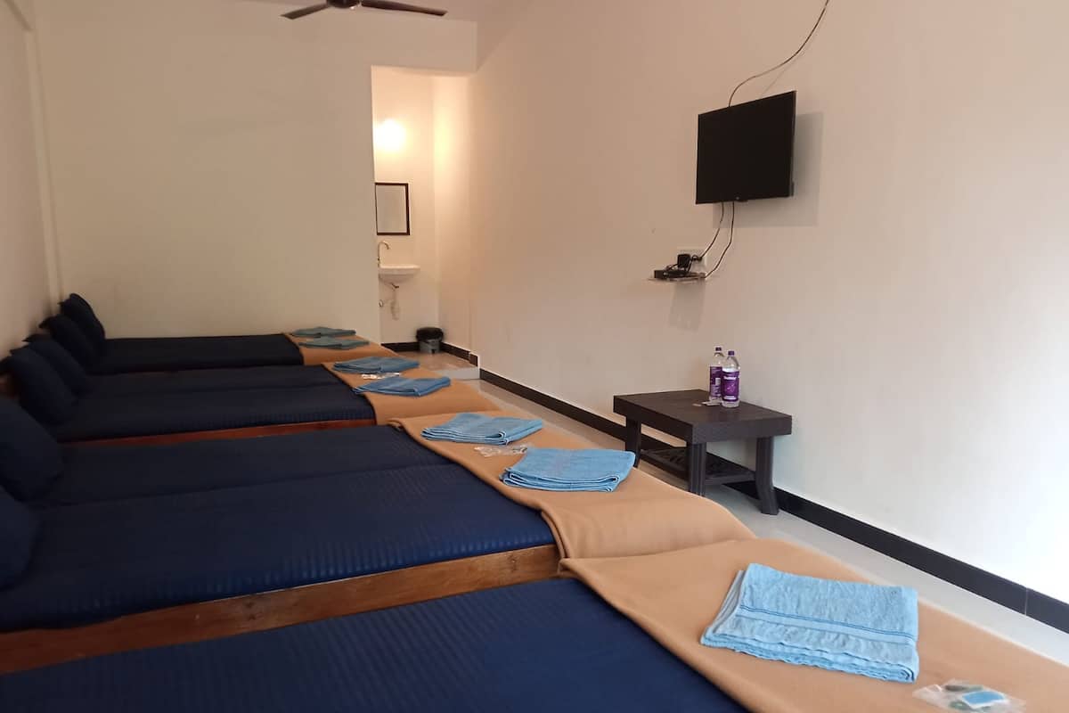 Reihe von Massageliegen mit Handtüchern, ein kleiner Tisch mit Flaschen und ein Fernseher an der Wand.