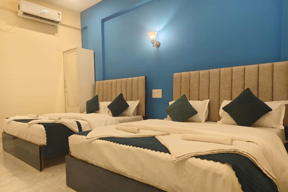 Ein Hotelzimmer mit zwei Betten, beigen Kopfteilen und einer blauen Akzentwand.