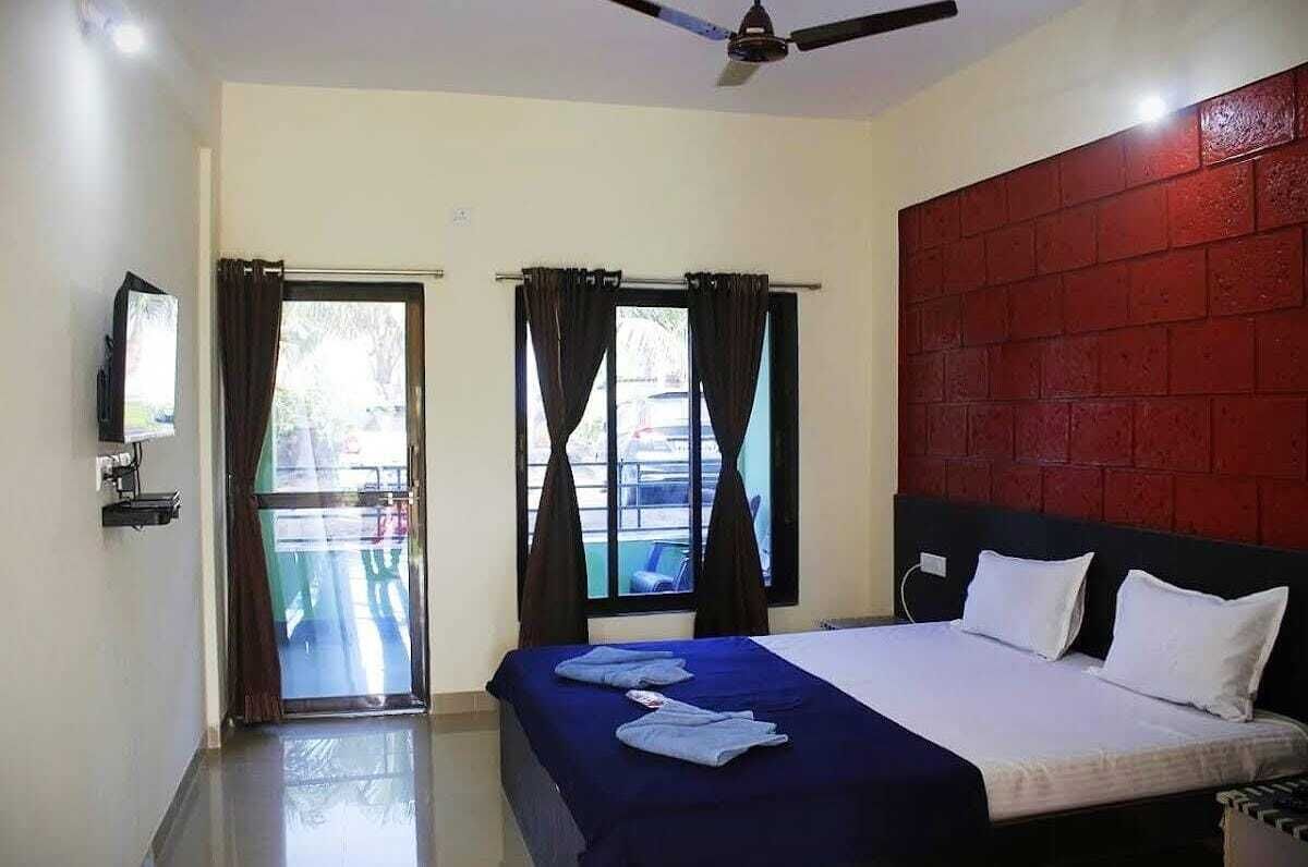 Una habitación de hotel con una cama, un televisor, un ventilador de techo y una pared de ladrillo rojo.