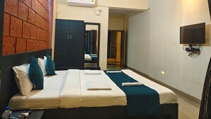 Habitación de hotel con una cama, un televisor montado en la pared, un ventilador de techo y una pared con diseño de ladrillo.