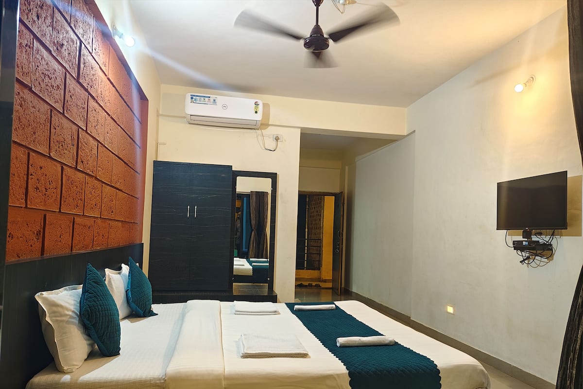 Ein Hotelzimmer mit Bett, Wandfernseher, Deckenventilator und einer Wand mit Backsteinmuster.