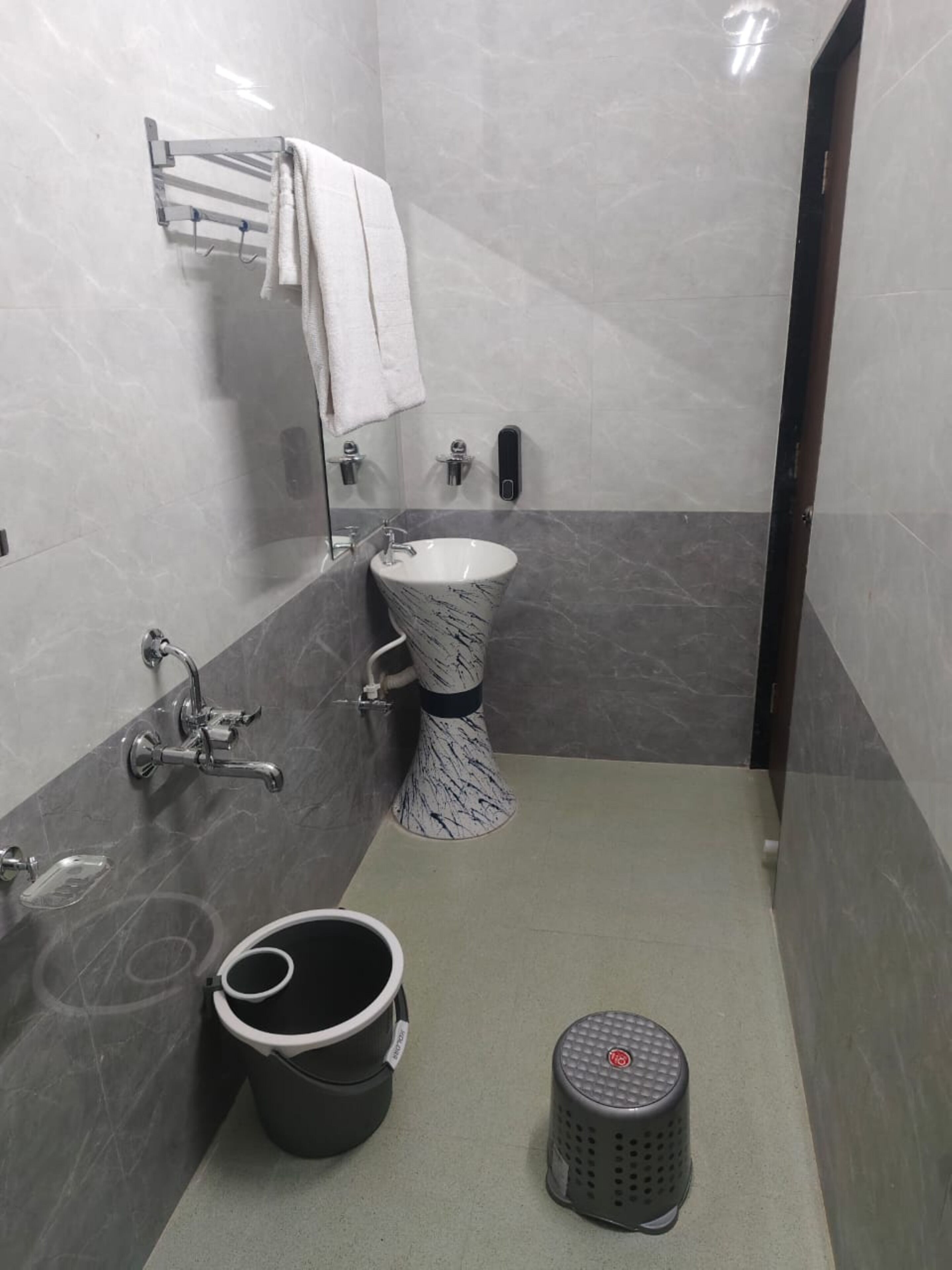 A modern bathroom with a marble sink, a toilet, a bathtub, and a small trash bin.