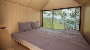 Une chambre avec une grande fenêtre, un lit et un mur en bois.