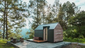 Une petite cabane avec un toit en pente, une porte en bois et un banc à l’extérieur.