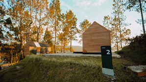 Une cabane portant l’inscription « Cabane 2 », située dans une zone boisée sous un ciel dégagé.