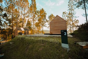 Uma cabana com a inscrição 'Cabin 2' numa área arborizada, com céu claro.