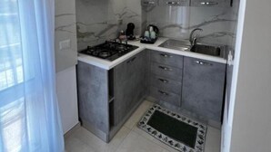 A compact kitchen with a gas stove, a range hood, a sink, and a small countertop area. - Apartment*3 Virgilio Lamezia Airport "FANTASIA" (Santa Eufemia Lamezia)