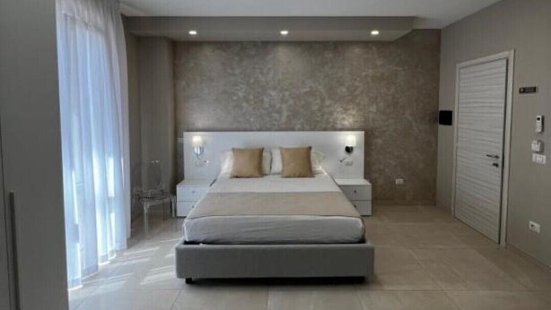 A modern bedroom with a large bed, recessed ceiling lights, a built-in headboard, and a sliding door closet. - Apartment*3 Virgilio Lamezia Airport "FANTASIA" (Santa Eufemia Lamezia)