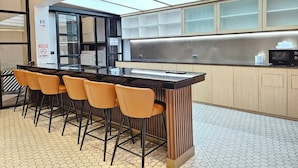 A modern kitchen with a central island, bar stools, and a microwave. - 14 Sathorn hotel (Bangkok)