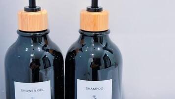 Two bottles of shower gel and shampoo on a bathroom counter.