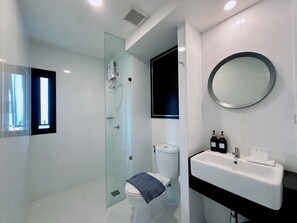 A modern bathroom with a glass-enclosed shower, a toilet, a sink with a mirror, and a window. - 14 Sathorn hotel (Bangkok)