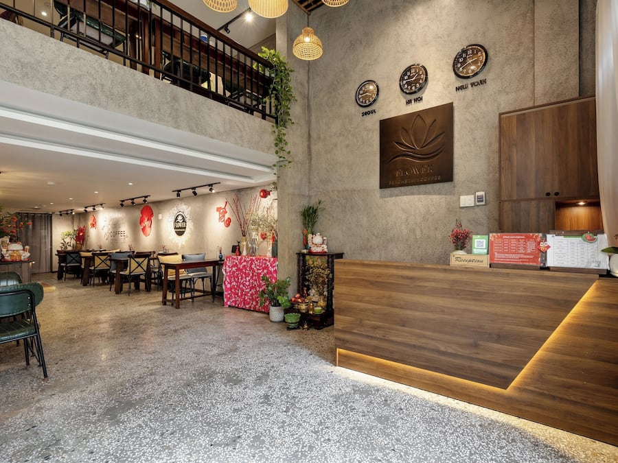 A spacious lobby with a wooden reception desk, multiple seating areas, and a mezzanine level.