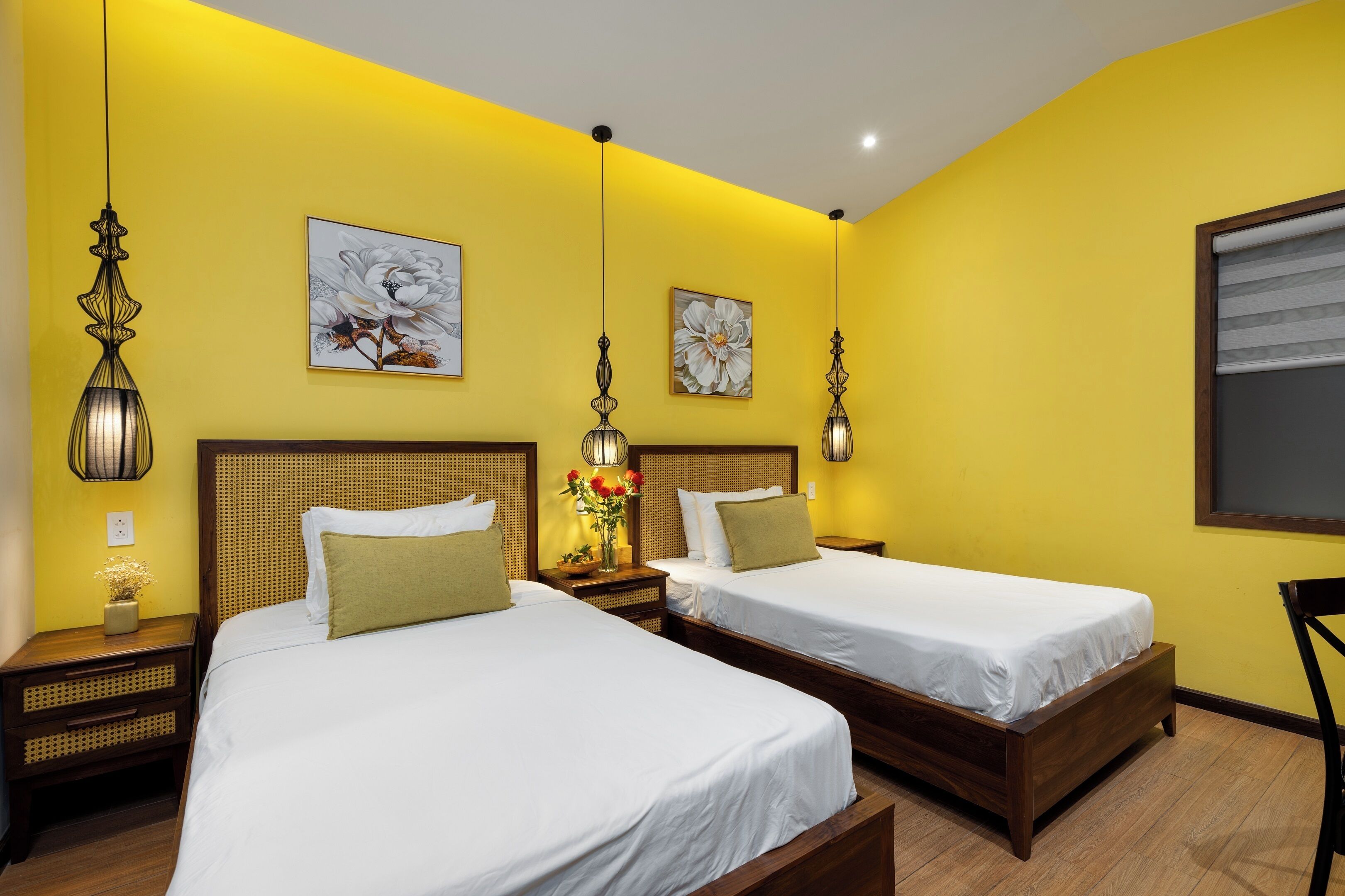 A hotel room with two beds, wooden headboards, and yellow walls.