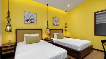A hotel room with two beds, wooden headboards, and yellow walls.